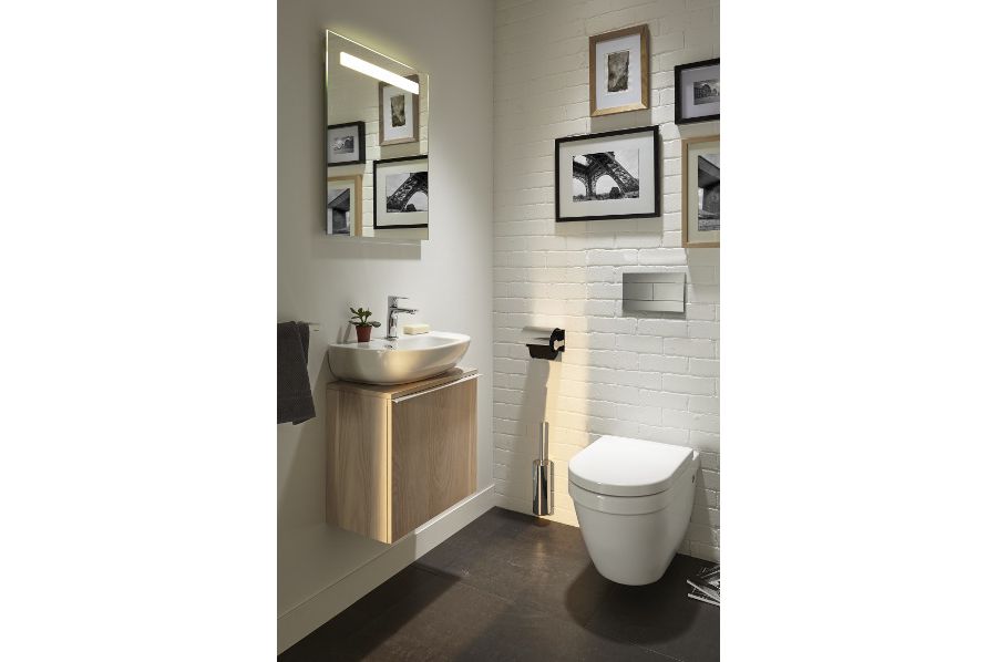 Des toilettes avec un meuble lave-mains en bois et des murs carrelés blancs