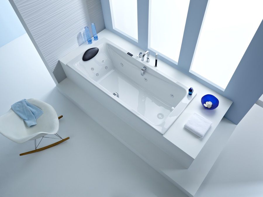 Une baignoire blanche confortable avec des buses massantes et un repose-tête pour se détendre dans la salle de bains comme dans un spa