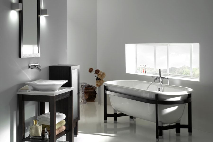 Une salle de bains épurée toute blanche avec une baignoire près de la fenêtre, un meuble vasque et une vasque