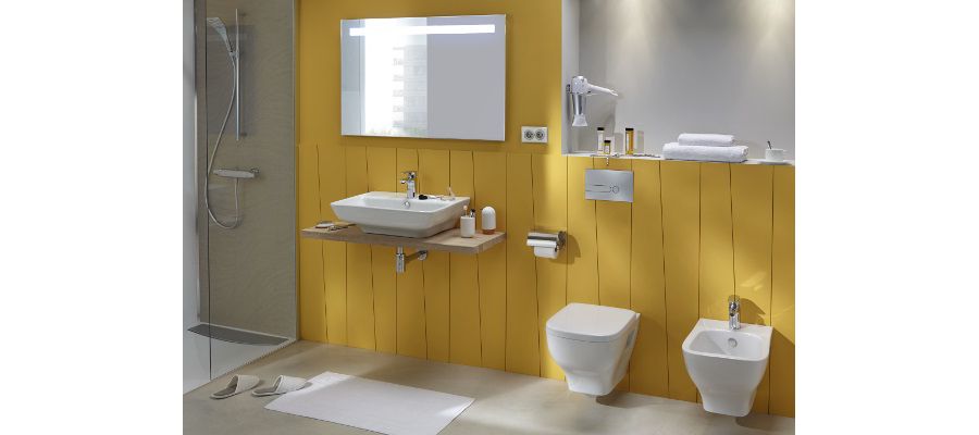 Une salle de bains avec des murs en bois jaunes, un plan vasque et des WC