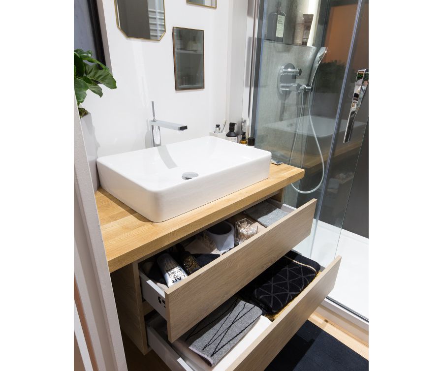Une salle de bains avec une douche et une vasque blanche sur un plan-vasque en bois