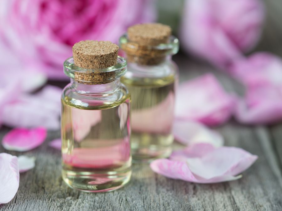Des fioles d'huiles essentielles et des pétales de roses pour parfumer la salle de bains